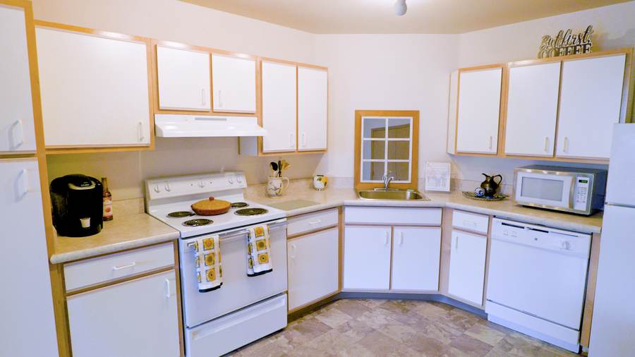 Full apartment kitchen with white cabinets and appliances