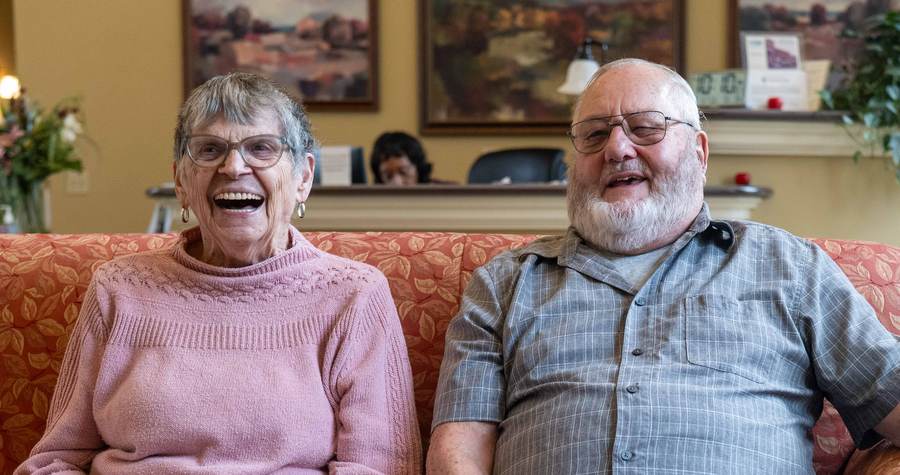 Two residents laughing together on a sofa
