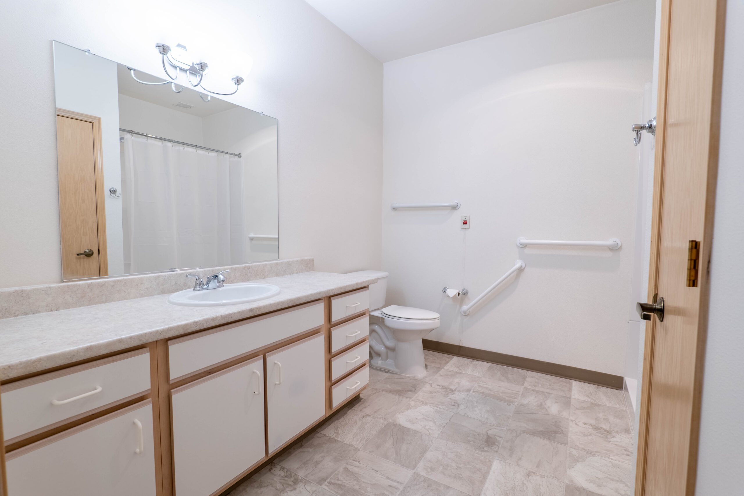 Apartment bathroom with grab bars and a long vanity